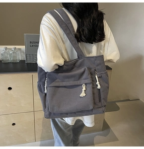 Détail du sac fourre-tout en velours côtelé gris foncé avec poche et gland blanc