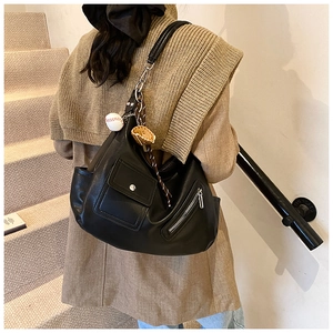 Détail d'un sac cabas en cuir texturé noir avec poche avant et breloque de baseball