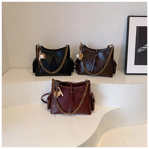Tre borse tote in pelle con catene dorate e ciondoli da baseball su scale bianche