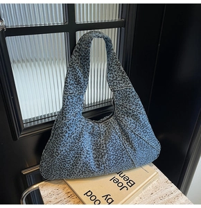 Detail of blue denim hobo bag with black leopard print and wide shoulder strap
