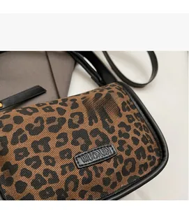 Détail du sac bandoulière en toile léopard avec logo MUONJIN et bordure noire