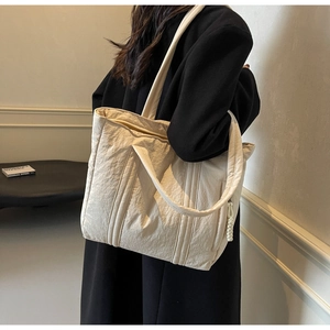 Close-up of cream tote bag with wrinkled texture, vertical stitching and knot detail