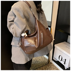Détail du sac bandoulière vintage en cuir PU marron avec plusieurs poches et pendentif