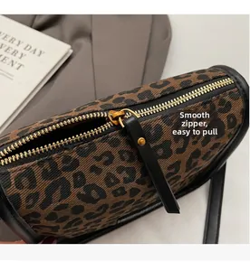 Gros plan sur un sac à main léopard avec fermeture éclair dorée fluide et bordure en cuir noir