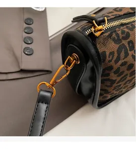 Détails du sac cylindre léopard avec garniture dorée et bandoulière en cuir noir