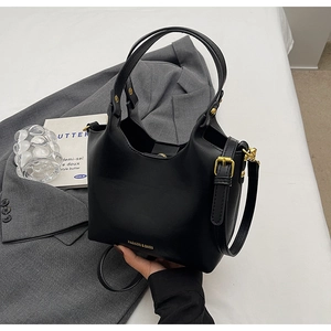 Détail du sac seau noir en cuir texturé avec des boucles en métal doré élégantes
