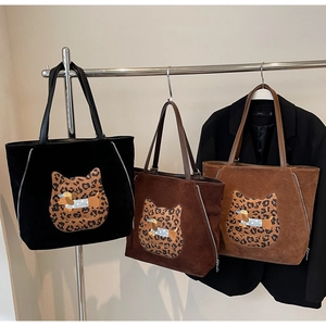 Detailed view of suede tote bags with leopard cat patch and cartoon dog embroidery