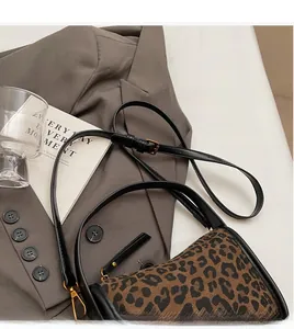 Détail d'un sac bandoulière léopard avec lanières en cuir noir et boucles dorées chic