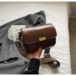 Detail of vintage dark brown crossbody bag with wide geometric pattern strap and gold buckle