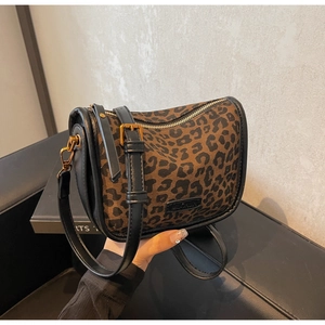 Gros plan sur un sac bandoulière léopard avec bordures en cuir noir et boucles dorées