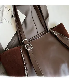 Detail of adjustable shoulder straps and silver buckles on a brown tote bag