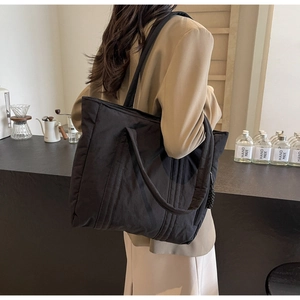 Detailed side view of a large black nylon tote bag on a model for casual office use