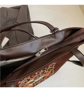 Close-up of smooth metal zipper on brown leather tote bag with leopard print details