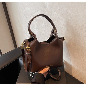 Détail du sac seau en cuir marron foncé avec texture et accessoires dorés élégants