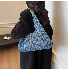 Detail showing blue leopard print denim fabric with frayed edges on oversized hobo bag