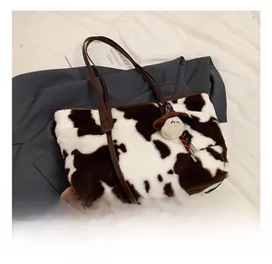 Close-up of cow print plush tote bag with brown straps and cute sheep charm accessory