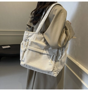 Détail du sac cabas en velours côtelé crème avec tirette en corde et poches multiples sur mannequin