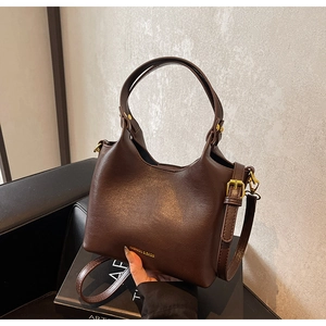 Détail du sac à main en cuir marron foncé avec ferrures dorées et texte de mode