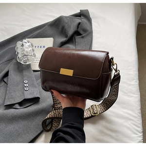 Detailed close-up of dark brown crossbody bag with retro woven wide shoulder strap
