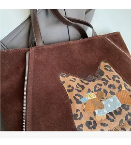 Detail of brown suede tote bag with leopard cat patch and puppy embroidery