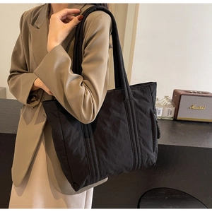 Detail of black nylon tote bag featuring a practical side zipper pocket for daily commute