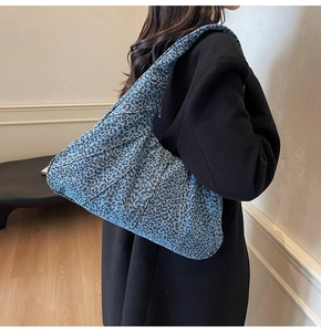 Detail of the blue leopard print denim underarm bag with diagonal stitching and wide strap