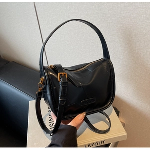 Détail de la texture du cuir noir et des ferrures dorées sur le sac polochon chic
