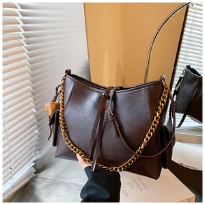 Dettagli di una borsa tote marrone scuro con catena dorata e nappe in pelle eleganti