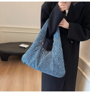 Detail of blue leopard print denim tote bag shown with an elegant black wool coat
