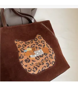 Detail of suede tote bag with leopard cat patch and puppy embroidery in dark brown