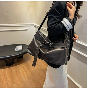 Detail view of large dark leather tote with metal buckle and silver eyelet shoulder strap