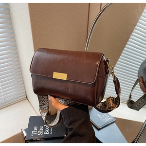 Detail of vintage brown crossbody pillow bag with chic patterned wide strap and gold buckle
