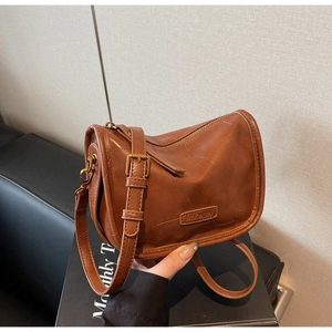 Détail d'un sac à bandoulière en cuir patchwork marron avec bandoulière réglable et ferrures