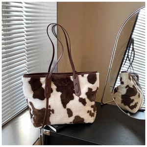 Macro shot of fluffy cow print plush fabric and brown leather strap on the tote bag