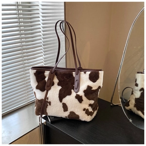 Detail of plush cow print tote bag with brown leather handles and soft faux fur texture