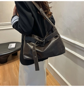 Deep brown faux leather tote bag detail with wide decorative belt buckle and smooth texture