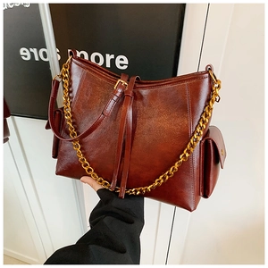 Dettaglio borsa tote in pelle cerata marrone scuro con catena dorata e tasca laterale