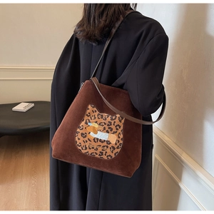 Detail of a large brown suede shoulder bag with leopard cat patch and dog embroidery