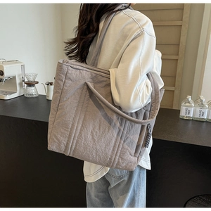 Detailed view of greyish-purple quilted tote bag with soft nylon texture and wide strap