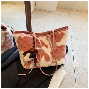 Close-up of pink cow print plush tote bag featuring a cute puppy plush charm pendant