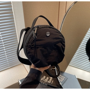Détail du sac rond noir en nylon avec logo argenté M FASHION et bandoulière réglable