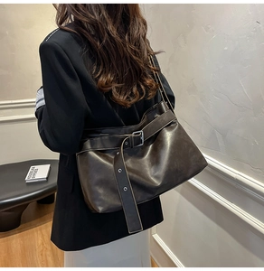 Detail of vintage brown leather tote bag with buckle strap on a walking model