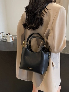 Sac seau chic en cuir noir mat avec lettrage doré et bandoulière pour femme élégante