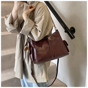 Dettaglio della borsa bordeaux con catena dorata e tasche laterali con patta elegante