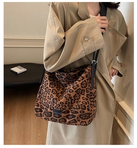 Detail of a large leopard print tote bag with black strap worn with a beige trench coat