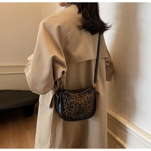 Détail d'un sac besace à motif léopard porté par un mannequin en trench beige