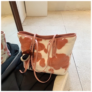 Detail view of pink and white cow print plush tote bag with a cute mushroom charm
