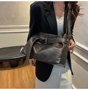Detail of dark brown tote bag featuring retro buckle element and adjustable wide shoulder strap