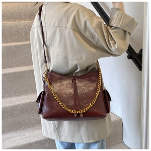 Vista laterale della borsa in pelle bordeaux con glitter dorati e catena in metallo