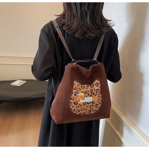 Detail of a brown suede backpack featuring a leopard cat patch with a dog embroidery